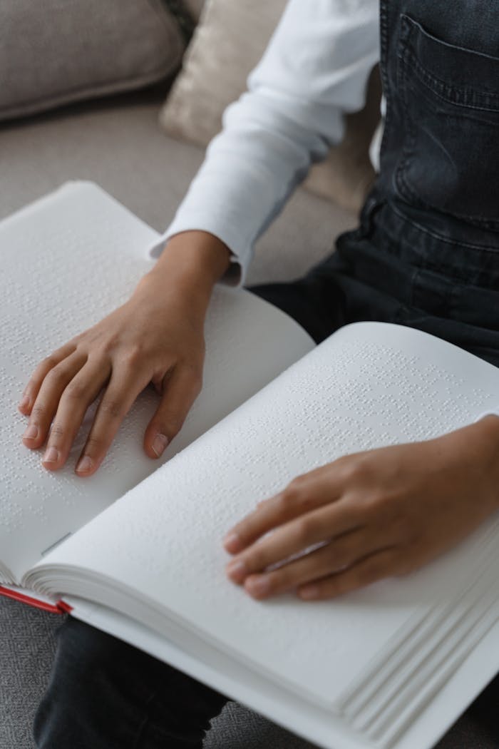 Close-up of child's hands reading a Braille book, emphasizing tactile learning.