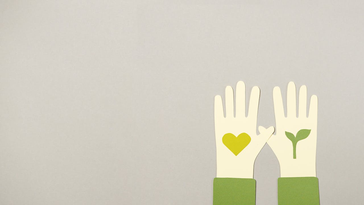 Paper cutout hands with eco symbols on gray background, symbolizing love and growth.